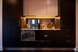 Gold accessories Photo of an eclectic kitchen in Sydney with a drop-in sink, dark wood cabinets, quartz benchtops, mirror splashback, stainless steel appliances and white benchtop.