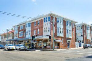 Inspiration for a mid-sized traditional one-storey brick red apartment exterior in Sydney with a flat roof and a mixed roof.