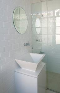 Inspiration for a small contemporary bathroom in Sydney with flat-panel cabinets, white cabinets, an alcove shower, white tile, subway tile, white walls, cement tiles, a vessel sink, engineered quartz benchtops, beige floor and a hinged shower door.