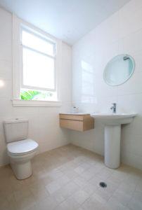 Design ideas for a mid-sized contemporary bathroom in Sydney with a two-piece toilet, white tile, porcelain tile, white walls, ceramic floors, a pedestal sink and beige floor.